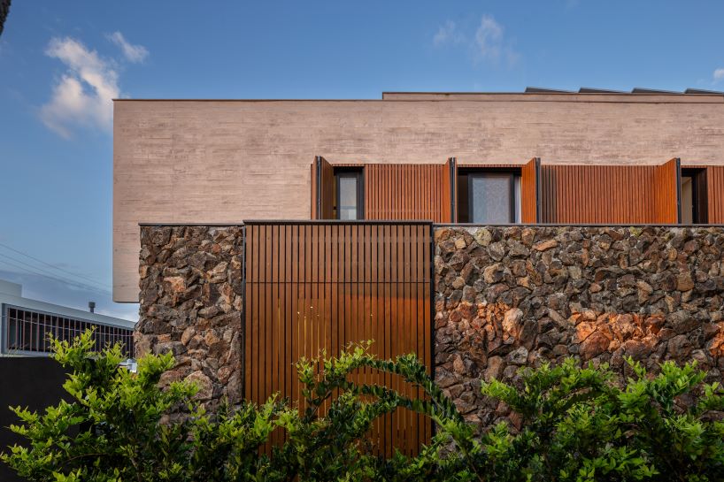 Oficina conceito arquitetura's cantilevered house rests on a stone volume in Brazil