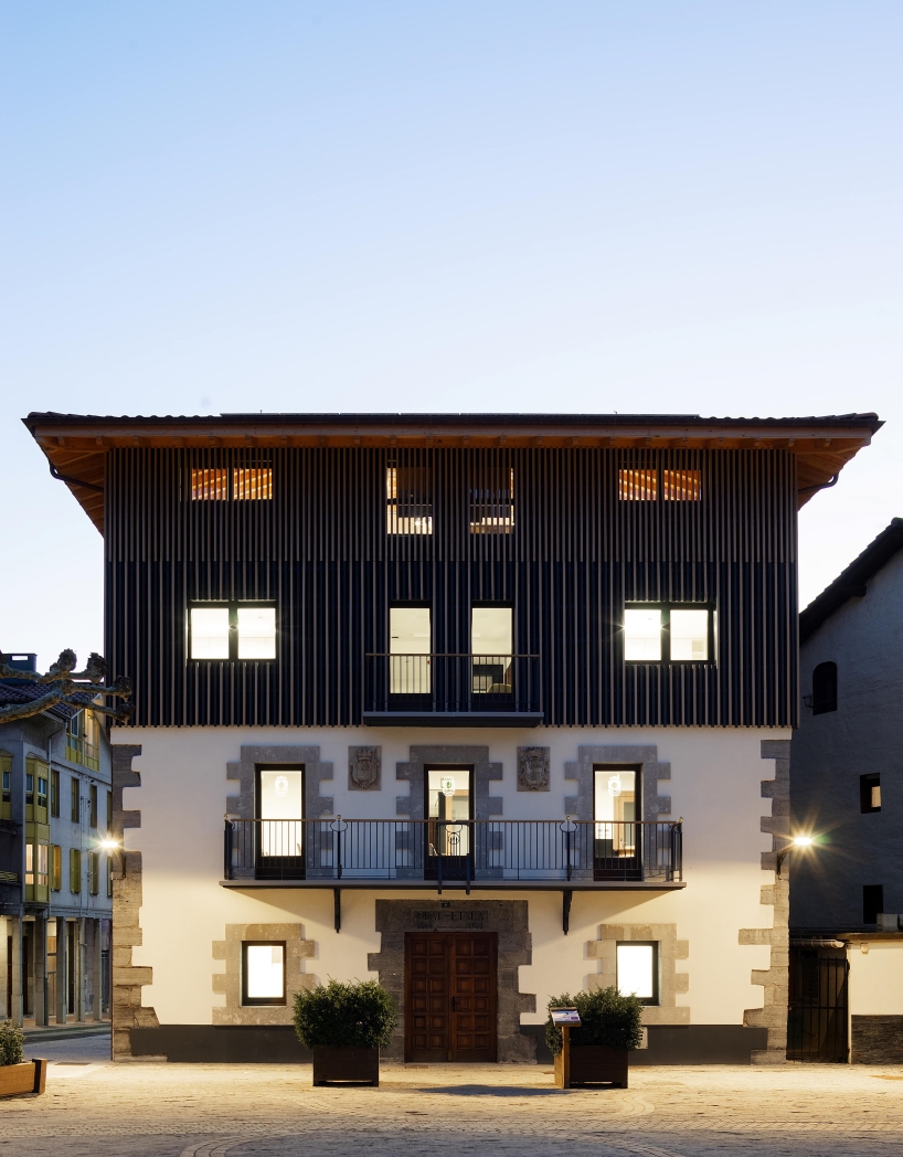 vertical wooden slats clad irura town hall's polyhedral facade in spain