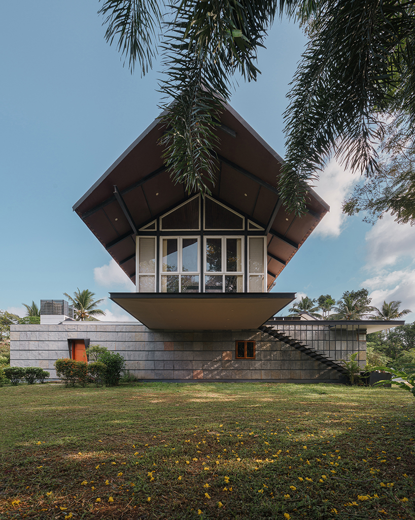 pitched roof volume cantilevers from thomas parambil's house amid kerala paddy fields