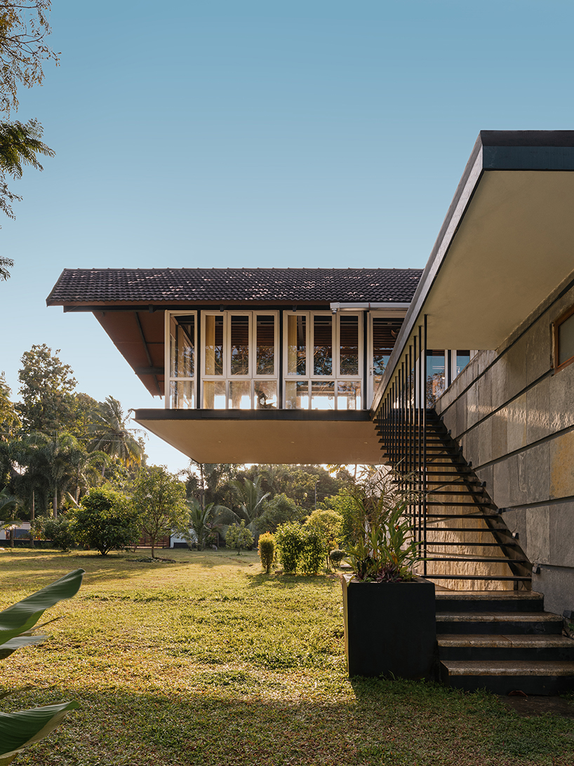 pitched roof volume cantilevers from thomas parambil's house amid kerala paddy fields