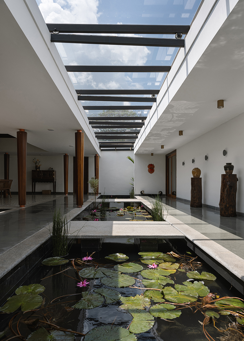 pitched roof volume cantilevers from thomas parambil's house amid kerala paddy fields