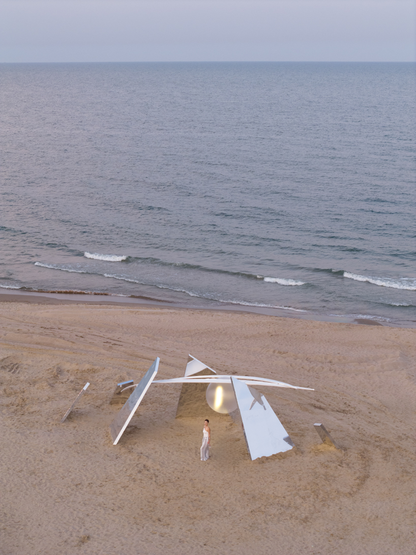 two suspended white wings float around luminous central sphere for oas/s-nest installation