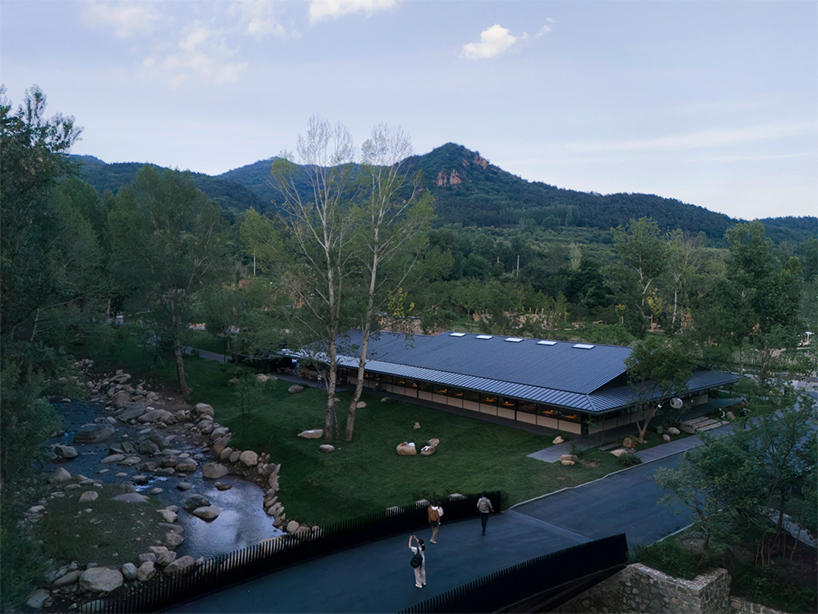 dark metal roof shapes community canteen beside mountain stream in china - 2