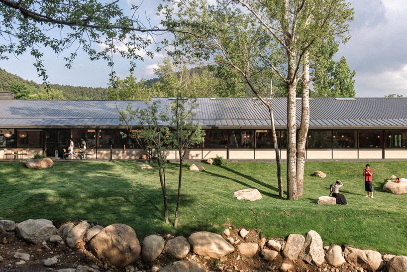 dark metal roof shapes community canteen beside mountain stream in china - 4