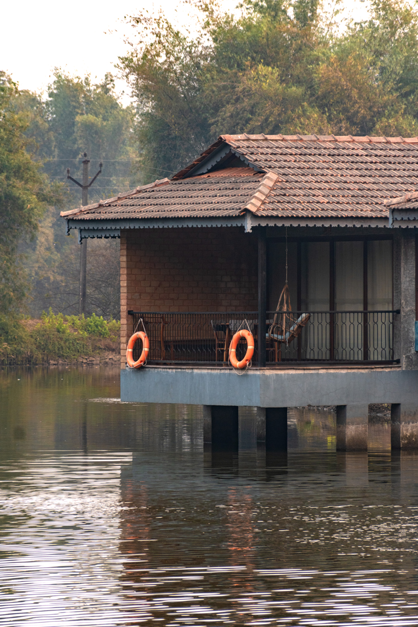 pond houses crafted from earth blocks float above land and water in india