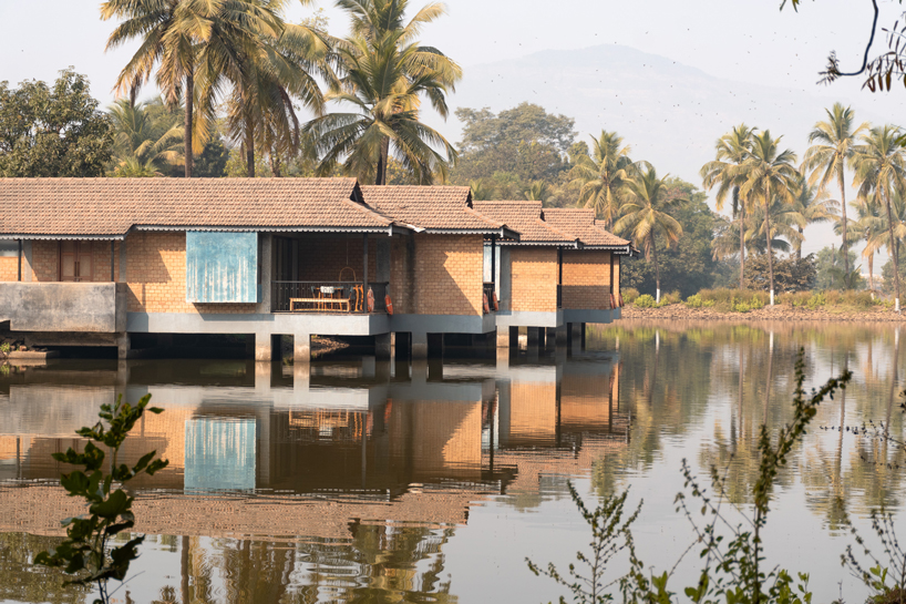 pond houses crafted from earth blocks float above land and water in india