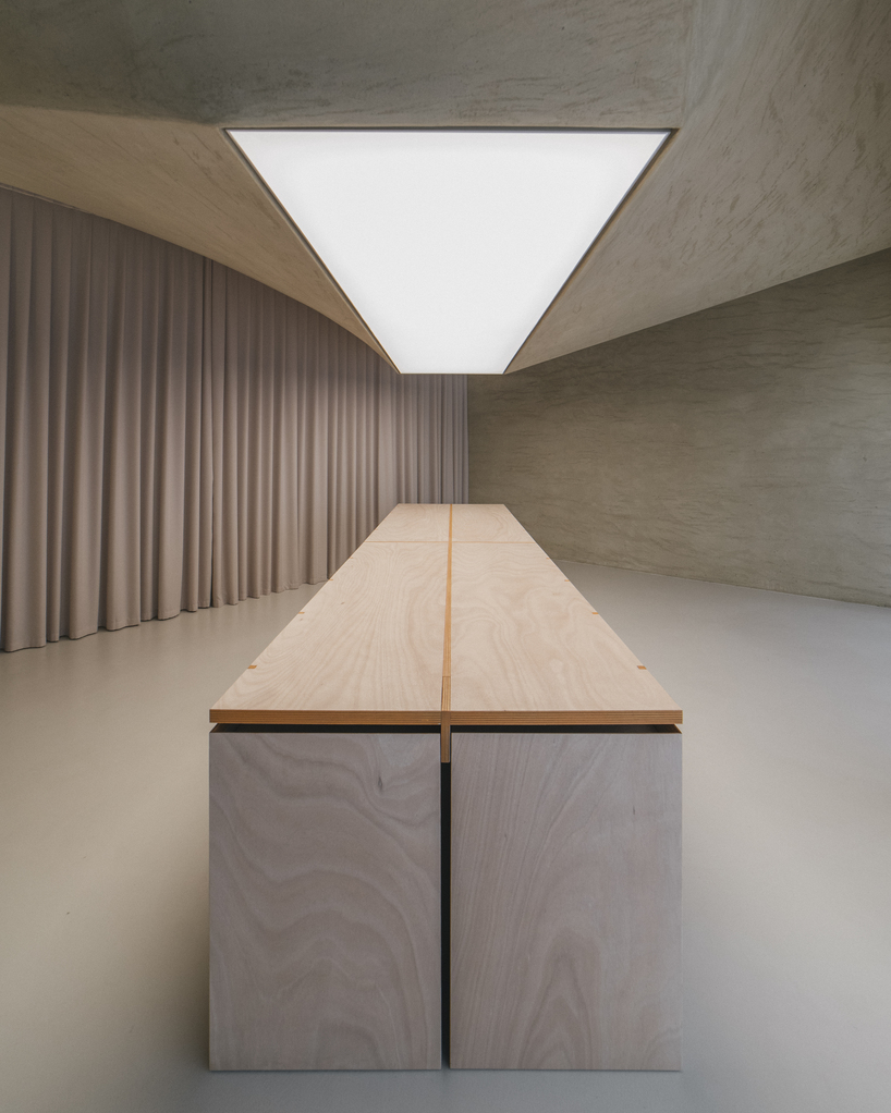 modular wooden table reforms into exhibition platform within ceramic workshop by AACM