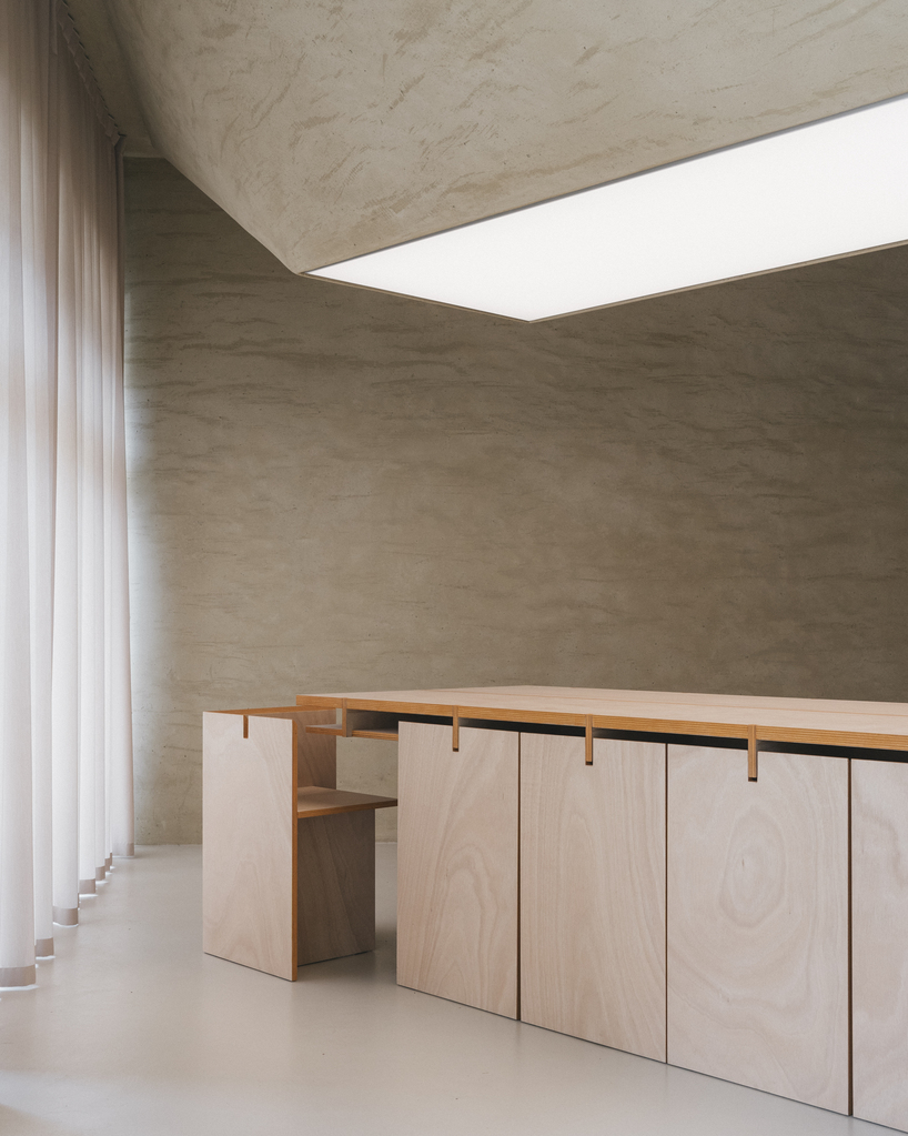 modular wooden table reforms into exhibition platform within ceramic workshop by AACM