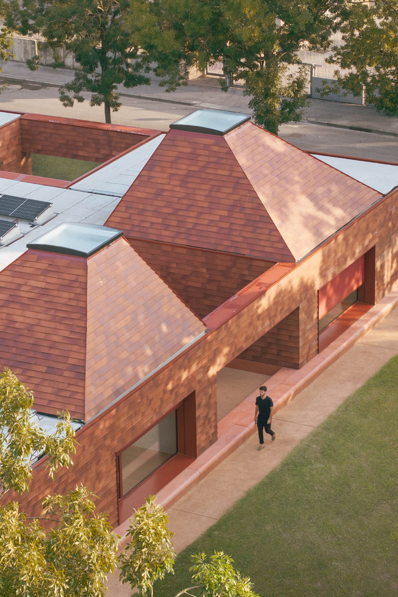 a cluster of terracotta-tiled pyramidal houses envelopes kindergarten in italy - 4