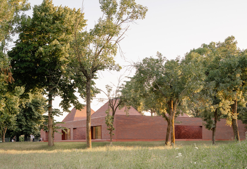 a cluster of terracotta-tiled pyramidal houses envelopes kindergarten in italy - 1