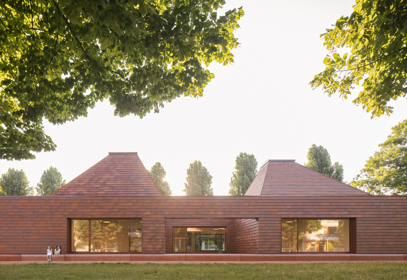 a cluster of terracotta-tiled pyramidal houses envelopes kindergarten in italy - 2