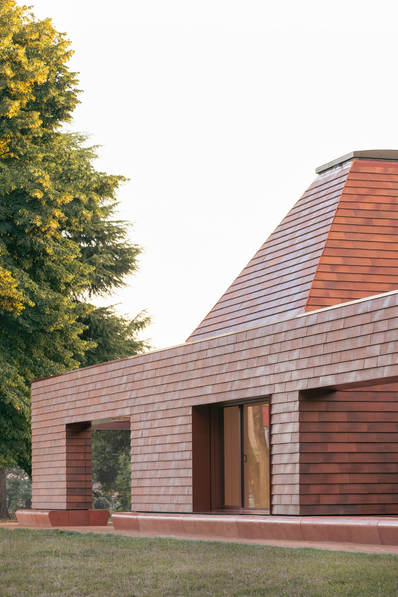 a cluster of terracotta-tiled pyramidal houses envelopes kindergarten in italy - 5