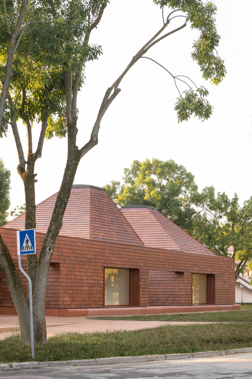 a cluster of terracotta-tiled pyramidal houses envelopes kindergarten in italy - 3