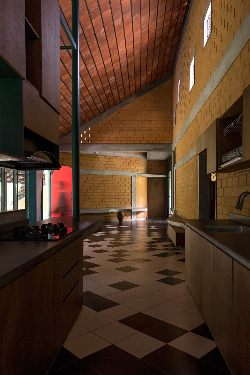 a semi-circular porous brick house stands amid rubber plantation in india