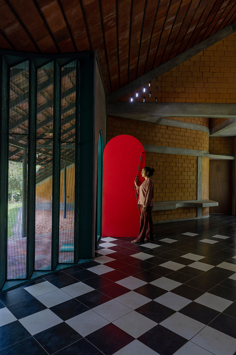 a semi-circular porous brick house stands amid rubber plantation in india