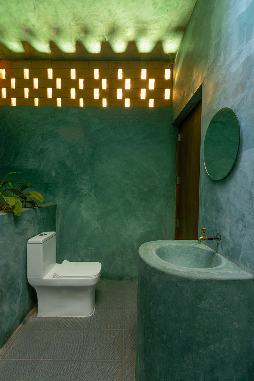 a semi-circular porous brick house stands amid rubber plantation in india