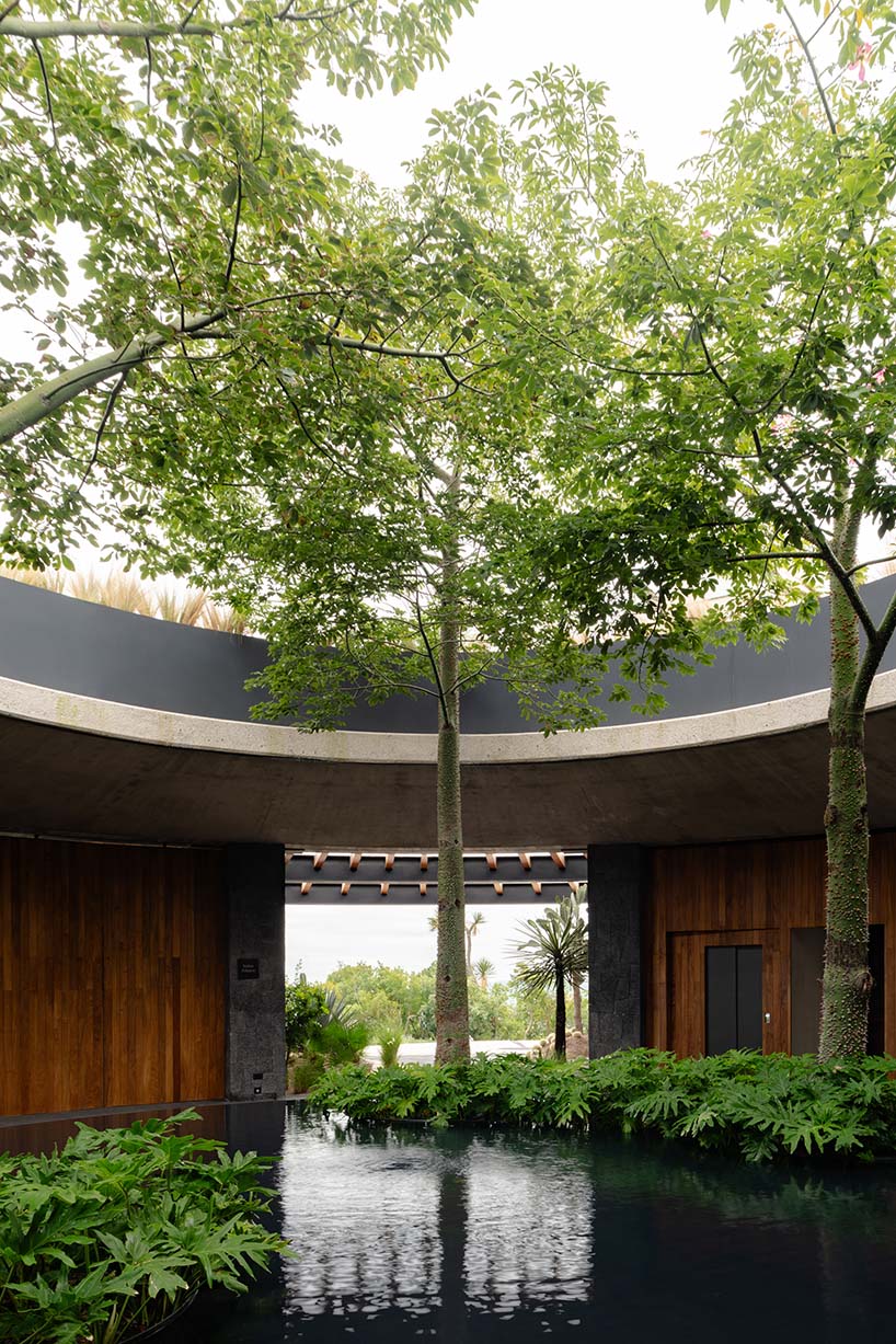 curved stone pavilion encloses circular reflecting pool for clubhouse in mexico