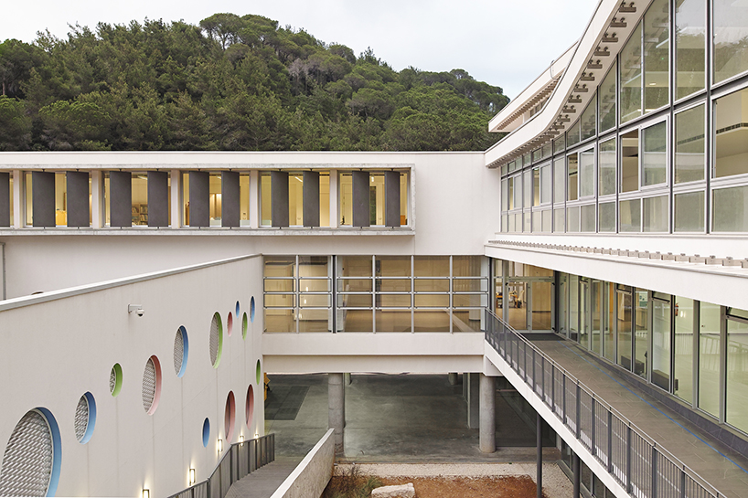 circular colored openings pierce through concrete facade of school extension in lebanon