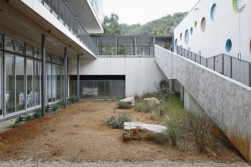 circular colored openings pierce through concrete facade of school extension in lebanon