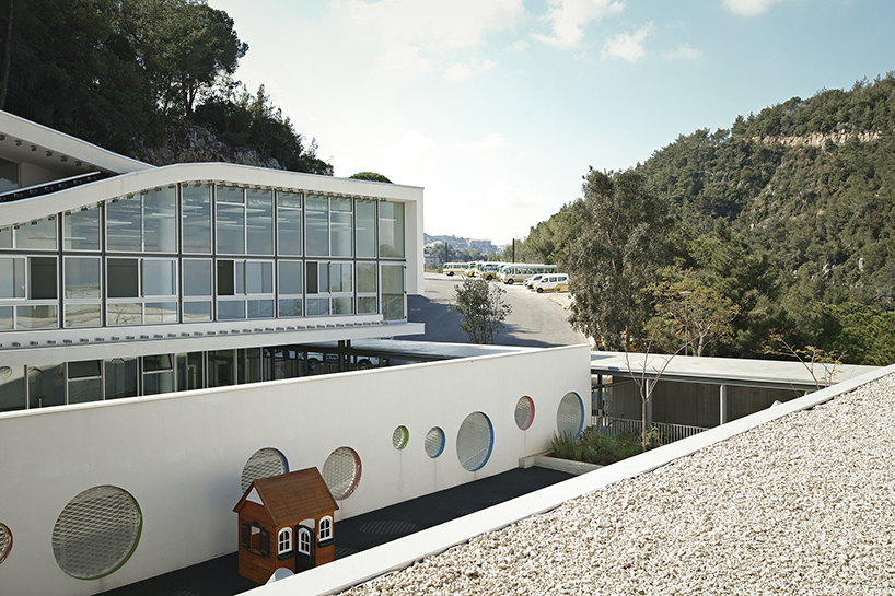 circular colored openings pierce through concrete facade of school extension in lebanon