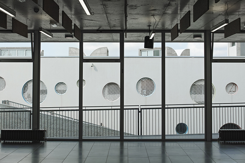 circular colored openings pierce through concrete facade of school extension in lebanon