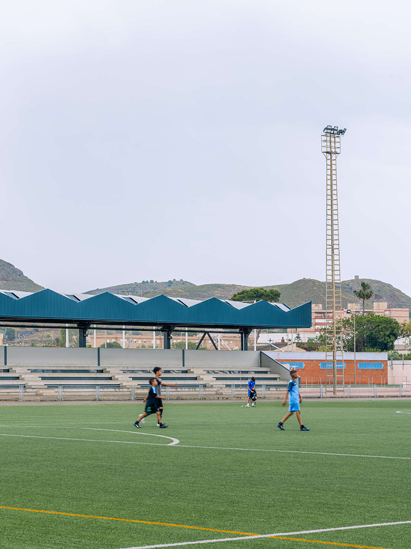 ribbed lime-green gateway and blue solar canopy reform municipal sports center in spain - 4