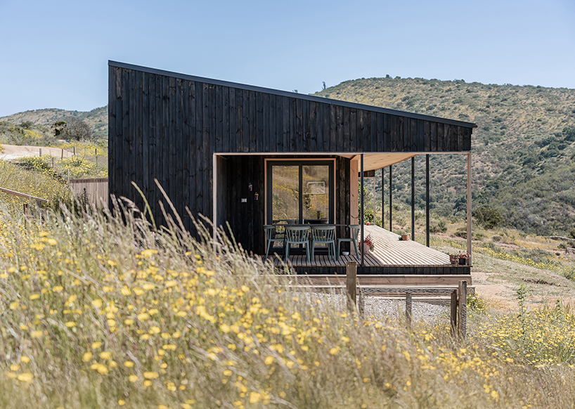 pitched roof tops linear casa las tupas, clad in charred timber in northern chile