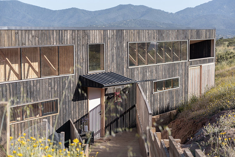pitched roof tops linear casa las tupas, clad in charred timber in northern chile