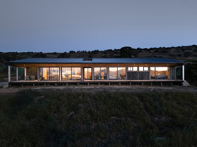 charred timber wraps linear casa las tupas, topped with pitched roof in northern chile