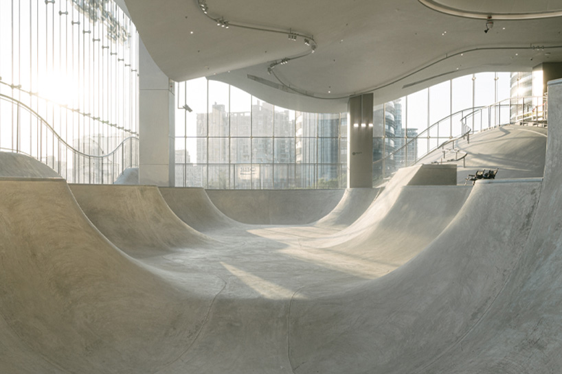 curved urban skatepark set within floating glass volume overlooks shanghai’s skyline