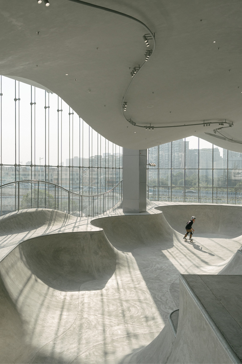 curved urban skatepark set within floating glass volume overlooks shanghai’s skyline