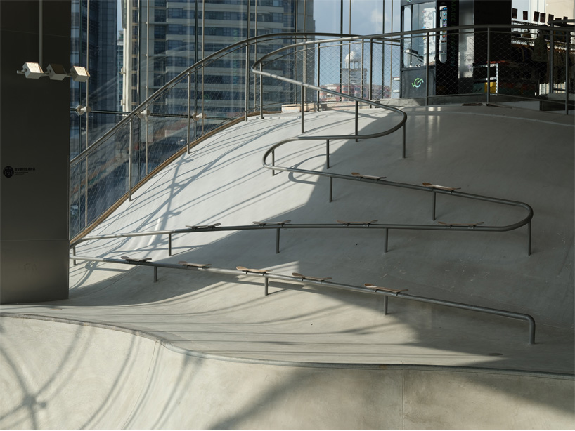 curved urban skatepark set within floating glass volume overlooks shanghai’s skyline