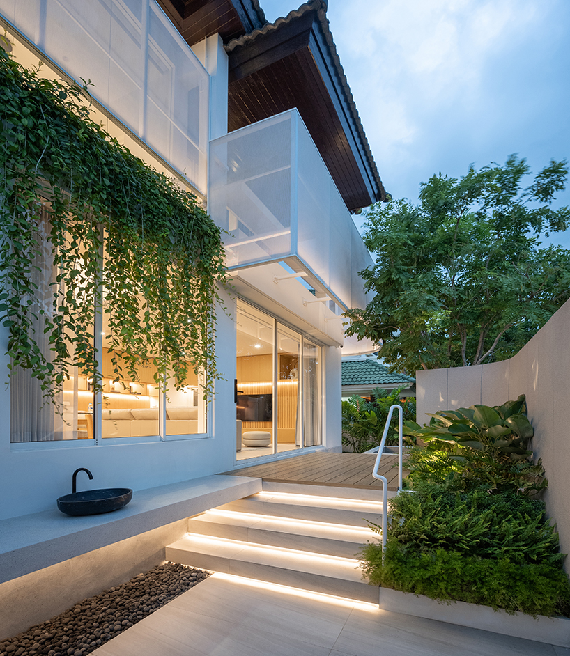 curved textile facades wrap reborn house in bangkok village emitting soft glow