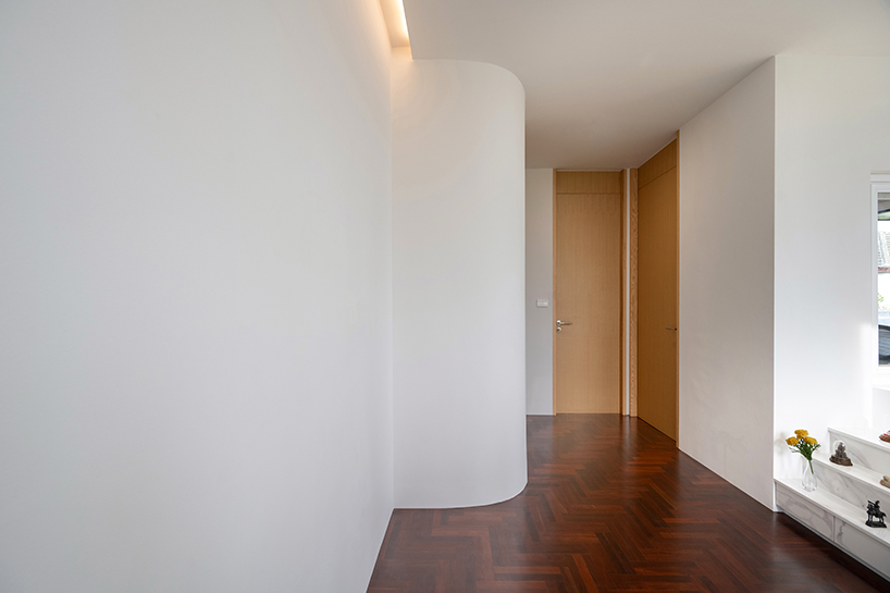 curved textile facades wrap reborn house in bangkok village emitting soft glow