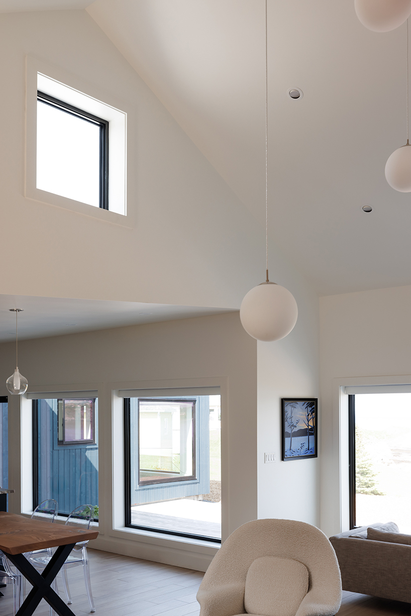 contrasting gable and mono-pitched metal roofs top wooden coley's point house in canada