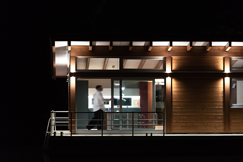 mono-pitch roof shields compact wooden cabin floating along river in serbia