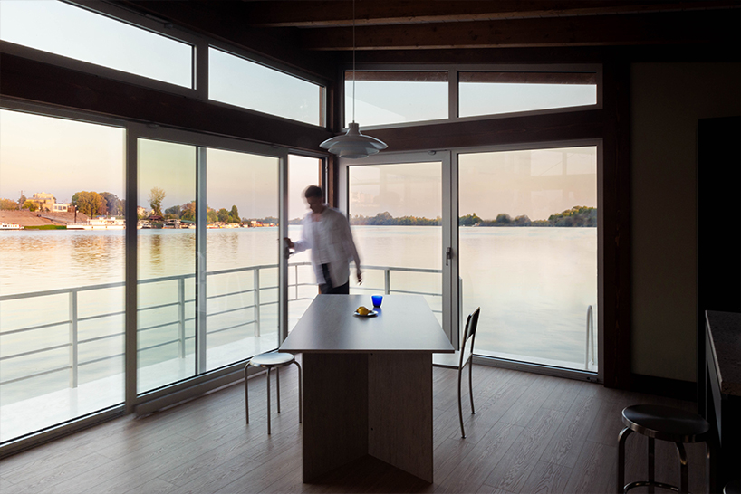 mono-pitch roof shields compact wooden cabin floating along river in serbia