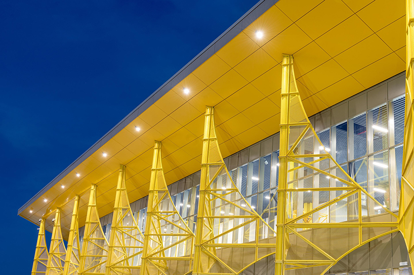 semi-transparent yellow metal arches frame airport&rsquo;s terminal extension in romania