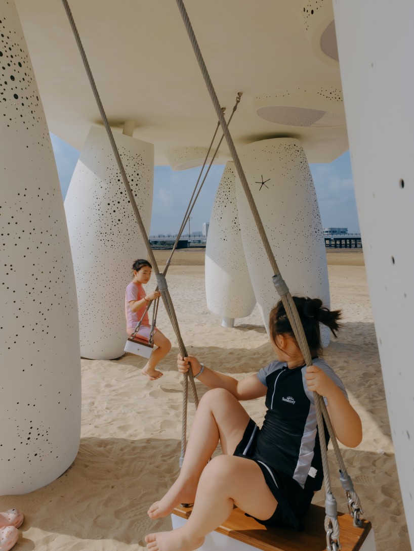 white stainless-steel cylinders form coral-like swing installation on chinese coast - 6