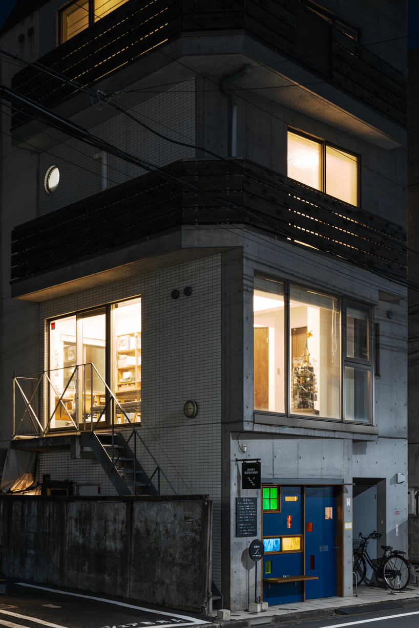 colored glass apertures reveal lively tokyo bar through bright blue entrance