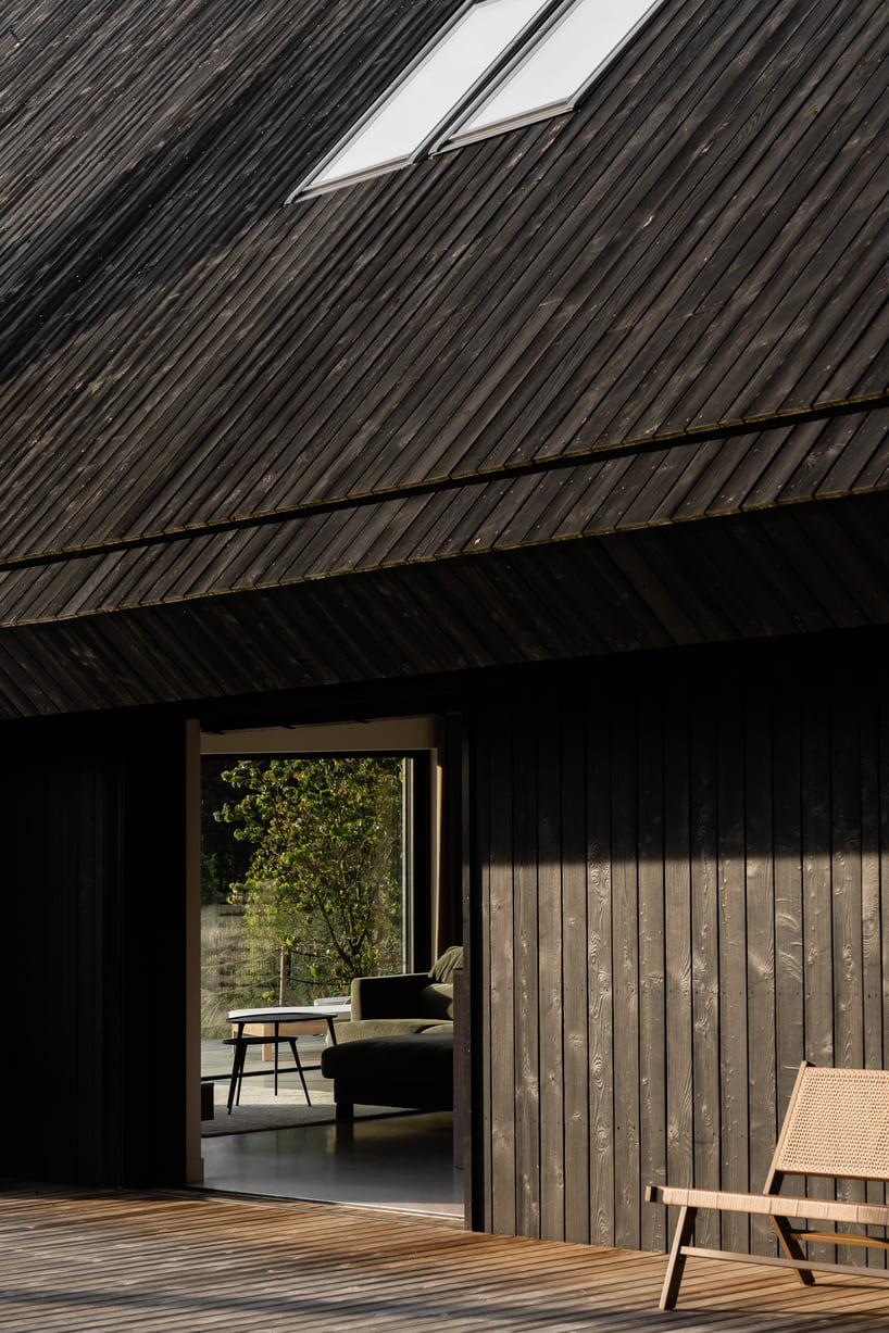 dark timber A&A house reinterprets traditional barn form within polish pine forest - 4