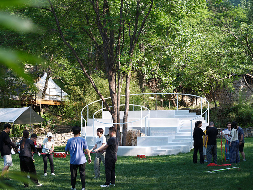 steel rings and stepped platforms spiral around trees in landscape gathering installation - 8