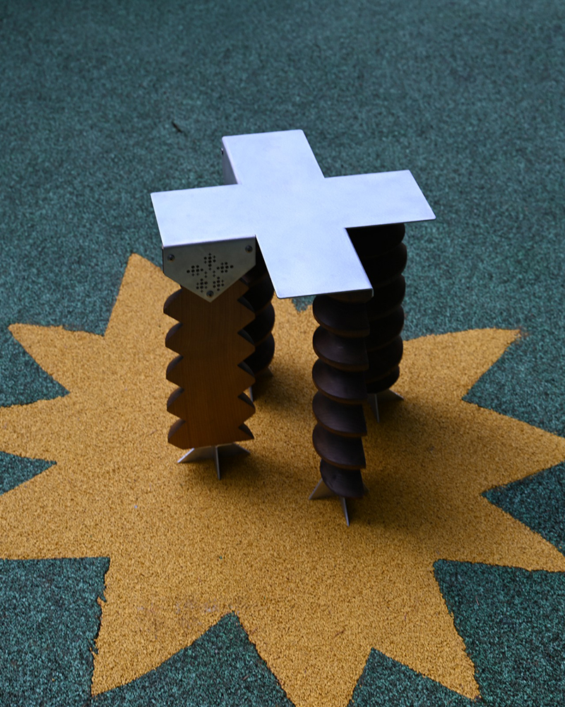 side view of the sculptural stool showing its wooden legs and geometric metal frame