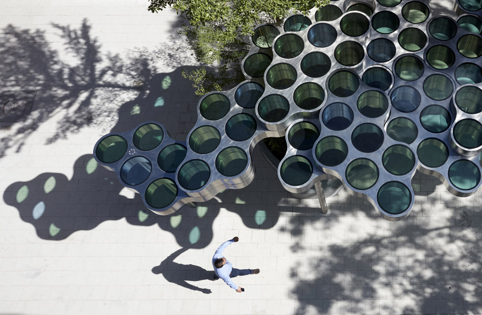the sun shines through the steel and colored glass structure that mimics cloud apertures