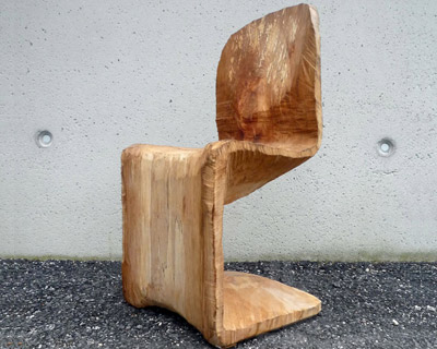 a chainsaw carves the wooden panton chair from a beech tree