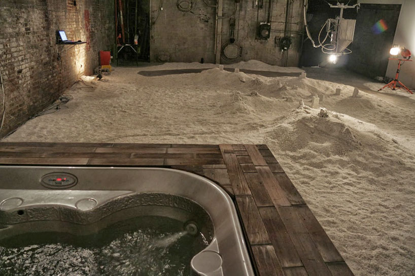 robot builds salt sculptures as visitors watch from a hot tub
