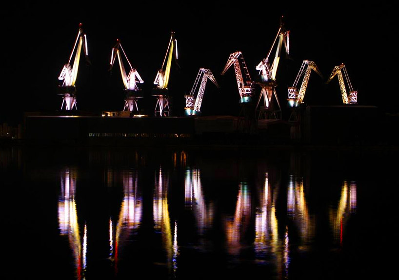 skira's illuminated shipyard cranes look like orgami in the sky