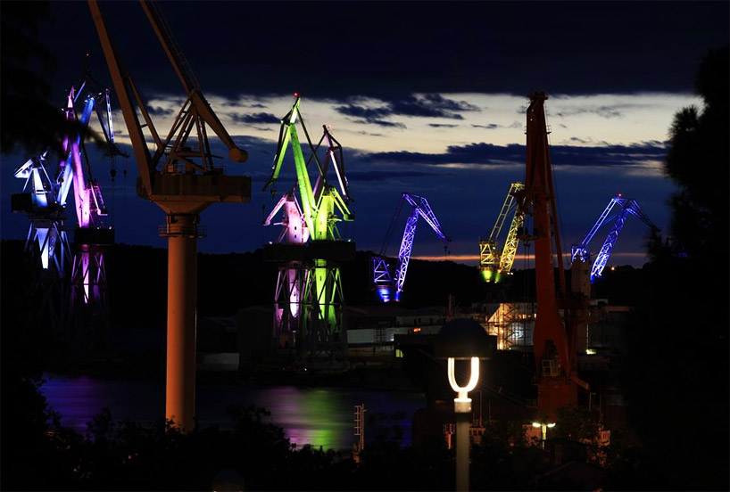 skira's illuminated shipyard cranes look like orgami in the sky