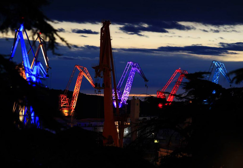 skira's illuminated shipyard cranes look like orgami in the sky