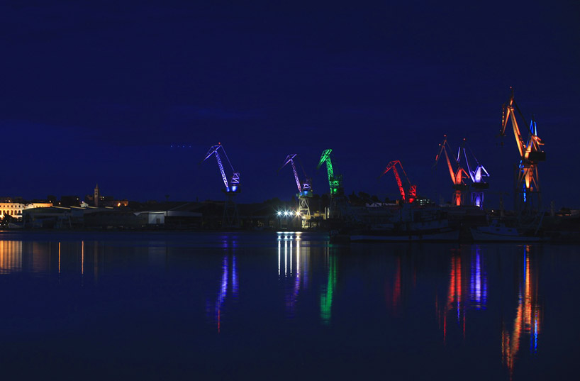 skira's illuminated shipyard cranes look like orgami in the sky